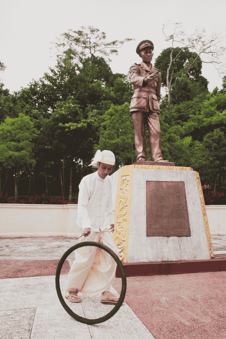 Moe Satt. 'Bicycle Tyre Rolling Event from Yangon (Bogyoke Aung San's Bronze Statue)'. 2013. Print on dibond, 91 x 60 cm. Collection of Singapore Art Museum. Image courtesy of Singapore Art Museum.